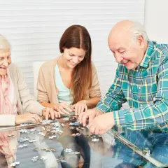 Trois personnes assemblent un puzzle, une activité ludique et stimulante, parfaite pour des jeux de mémoire pour seniors gratuit.