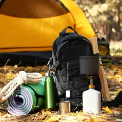 Sac à dos, tapis de sol, gourde, réchaud et bois pour un campement sur le chemin de Compostelle.