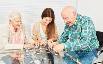 Trois personnes assemblent un puzzle, une activité ludique et stimulante, parfaite pour des jeux de mémoire pour seniors gratuit.