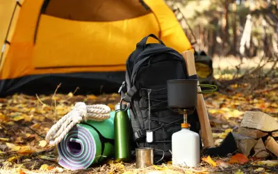 Sac à dos, tapis de sol, gourde, réchaud et bois pour un campement sur le chemin de Compostelle.