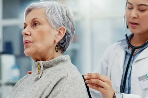 Médecin écoutant le souffle au cœur d'une patiente âgée avec un stéthoscope.