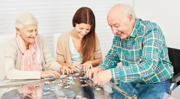 Trois personnes assemblent un puzzle, une activité ludique et stimulante, parfaite pour des jeux de mémoire pour seniors gratuit.