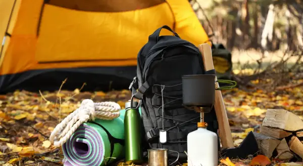 Sac à dos, tapis de sol, gourde, réchaud et bois pour un campement sur le chemin de Compostelle.