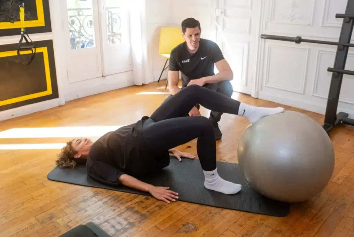 Un coach supervise une femme effectuant des exercices de rééducation avec une prothèse de hanche, évitant les mouvements interdits.
