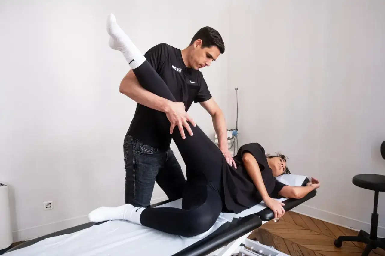 Un kin&eacute;sith&eacute;rapeute guide la jambe d'une patiente allong&eacute;e pour un exercice kin&eacute; hanche.