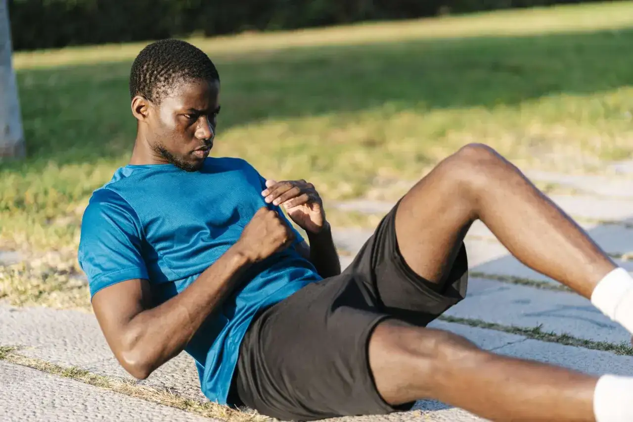 Un homme fait des abdominaux en plein air, un exercice pour perdre du ventre.