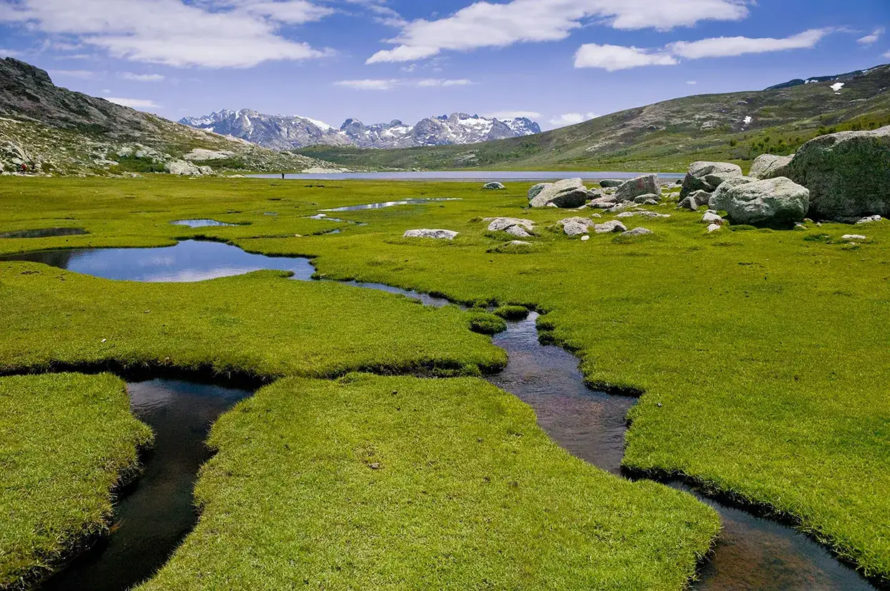 Paysage de montagne avec un lac, des ruisseaux serpentant dans une prairie verdoyante et des rochers. Quel est le gr le plus difficile &agrave; traverser ?