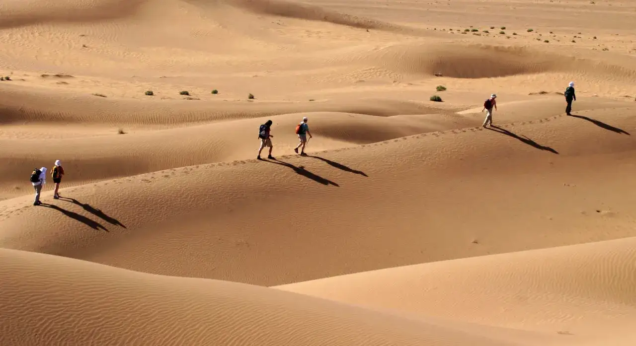 Un groupe de randonneurs s'aventure dans les dunes ondulantes du d&eacute;sert du Maroc pour un trek inoubliable.