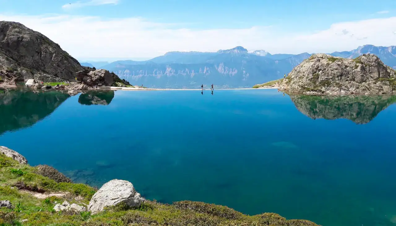 Lac alpin aux eaux bleues intenses, reflets des montagnes. Des randonneurs profitent du paysage, un moment gr 738 de sérénité.