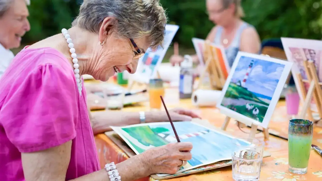 Un exemple d'animation pour personnes &acirc;g&eacute;es : des seniors peignent en plein air, concentr&eacute;s sur leurs toiles, dans une ambiance joyeuse et cr&eacute;ative.