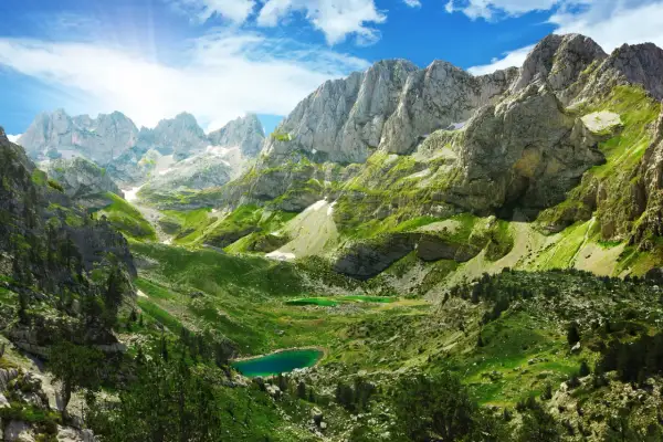 Magnifique paysage de montagne pour un trek en Albanie, avec des lacs d'un bleu profond et des pentes verdoyantes sous un ciel ensoleillé.
