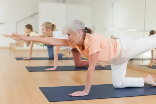 Des seniors en pleine forme sur un tapis, pratiquant un exercice de **parcours équilibre senior**.